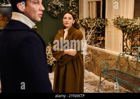 Ein fröhliches Paar begrüßt den Zauber des Winters, während es von Weihnachtsdekorationen umgeben ist. Stockfoto