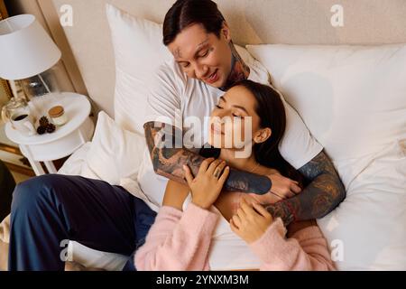 Ein Paar teilt intime Freude, während es sich auf weichen Betten in einem wunderschön gestalteten Zimmer entspannt. Stockfoto