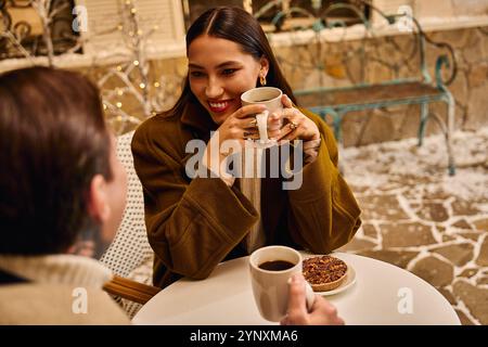 Das junge Paar teilt sich einen freudigen Moment bei heißen Getränken und Gebäck in einem charmanten Café. Stockfoto