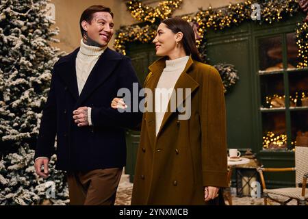 Junge Paare gehen Hand in Hand, teilen Lächeln und Wärme in einer bezaubernden Winterlandschaft Stockfoto