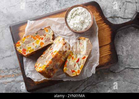 Festlicher gebackener Kuchen mit Hühnerleber, Karotten, Paprika, Kräutern und Eiern aus nächster Nähe auf einem Holzbrett auf dem Tisch. Horizontale Draufsicht von oben Stockfoto