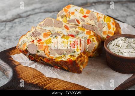 Scharfer Terrine-Kuchen mit Hühnerleber, Karotten, Paprika, Kräutern und Eiern aus nächster Nähe auf einem Holzbrett auf dem Tisch. Horizontal Stockfoto