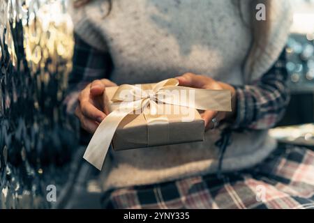 Nahaufnahme einer Frau, die drinnen sitzt und eine Geschenkbox mit einem Satinband bekommt Stockfoto