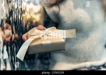 Nahaufnahme einer Frau, die drinnen sitzt und eine Geschenkbox mit einem Satinband bekommt Stockfoto