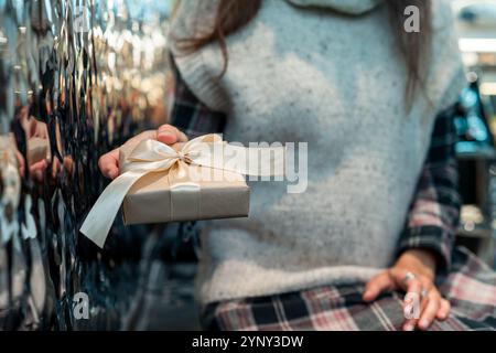 Nahaufnahme einer Frau, die drinnen sitzt und eine Geschenkbox mit einem Satinband bekommt Stockfoto