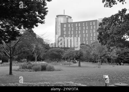 Portsmouth, Hampshire, England. 2. September 2024. Graue Landschaft im Victoria Park mit dem mehrstöckigen Travelodge hinter den Bäumen. Stockfoto