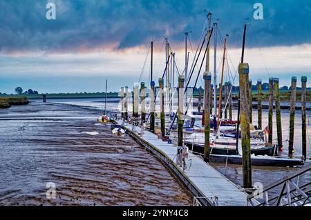 Boote, die in einem Jachthafen an der Ems bei Ebbe in Ostfriesland, Niedersachsen, Deutschland vor Anker gebracht wurden Stockfoto