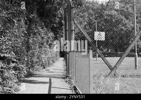 Gosport, Hampshire, England. 4. August 2024. Graustufenansicht auf einen schmalen Fußweg neben der HMS Sultan, Grange Road. Stockfoto