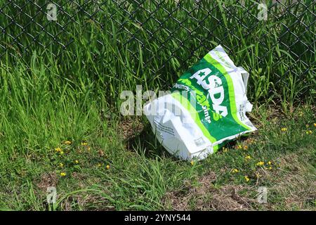 Gosport, Hampshire, England. 4. August 2024. Farbe, horizontal: Eine entsorgte Supermarkttragetasche auf Grünland. Stockfoto