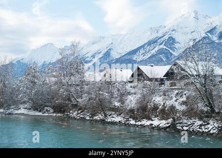 Reihen traditioneller Häuser am Fluss mit verschneiten Bergkulissen, Österreich Stockfoto