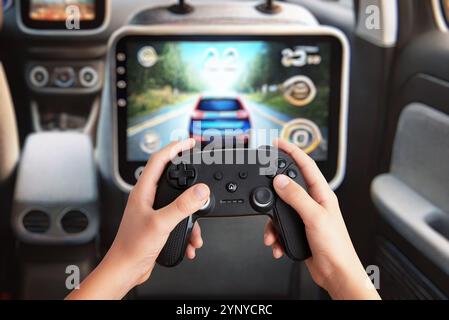 Spiele für Kinder auf einem Tablet auf der Rückseite des Beifahrersitzes, das ein Gamepad hält und Unterhaltung im Fond und tragbares Gaming in einem Auto zeigt Stockfoto