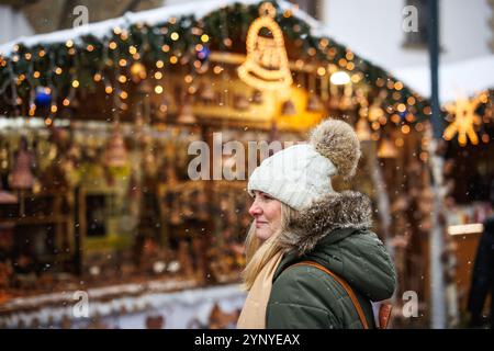 Frau genießt den Weihnachtsmarkt in der Stadt während der Adventsferien. Weihnachtsbeleuchtung und Dekoration am Marktstand Stockfoto