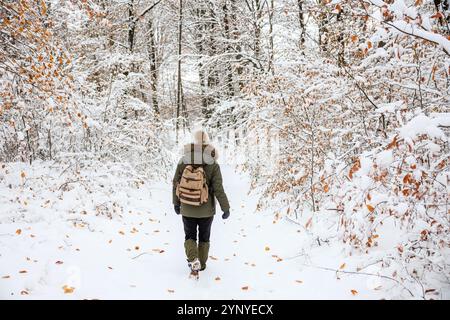 Wandern im Winterwald. Frau mit Rucksack läuft in verschneiten Wäldern Stockfoto