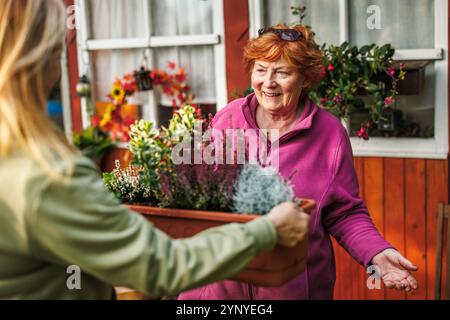 Berührender Moment der glücklichen lächelnden Seniorin und ihrer Tochter, die Blumen Pflanzen, ihre Bindung und Freude feiern, Zeit zusammen im Freien zu verbringen Stockfoto