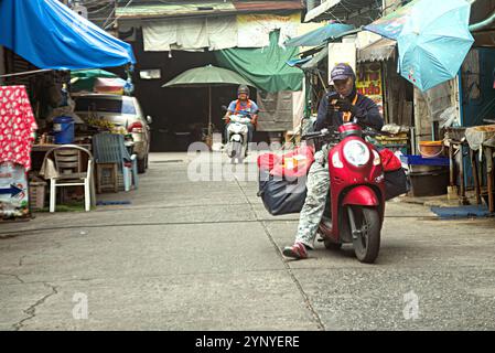 Pattaya, Thailand - 9. Oktober 2024: In der Innenstadt hat Ein junger Thai-Mann auf einem roten Motorrad sein iPhone überprüft. Stockfoto