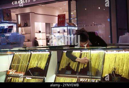 Pattaya, Thailand - 9. Oktober 2024: Terminal 21 Eine junge Thailändin mit einer weißen Gesichtsmaske prüfte den goldenen Schmuck. Stockfoto