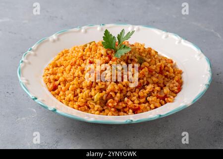 Traditioneller türkischer Bulgur-Pilaf mit Tomatensoße auf dem Teller (türkischer Name; Meyhane pilavi) Stockfoto