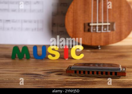 Wortmusik, Mundharmonika, Ukulele und Notenblätter auf Holztisch Stockfoto
