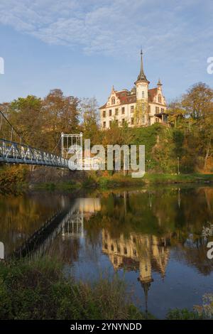 Burg auf einem Hügel mit Reflexion im Fluss, verbunden mit einer Brücke im Herbstlicht, Schloss Gattersburg, Hängebrücke, Fluss Mulde, Grimma, Le Stockfoto