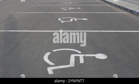 Reihe von Schildern auf Asphalt mit weißer Farbe, die einen Parkplatz für Menschen mit Behinderungen anzeigen, internationales Parkschild für Behinderte Stockfoto