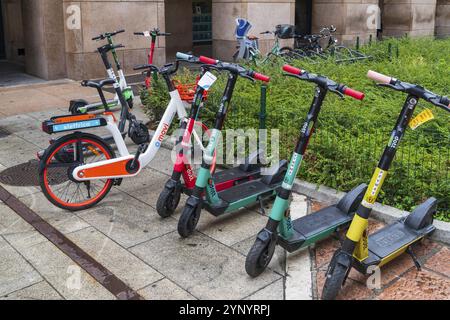 MAILAND, ITALIEN, 4. AUGUST 2021: Farbenfrohe Leihfahrräder und Motorroller auf einem Gehweg im Stadtzentrum von Mailand Stockfoto