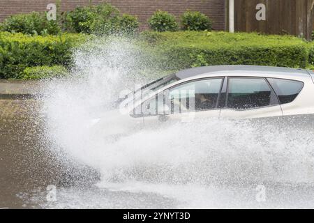 Das Auto fährt durch eine überflutete Straße Stockfoto