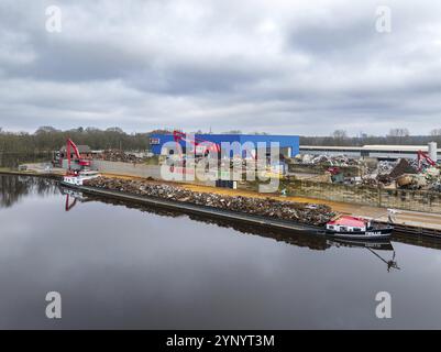 ALMELO, NIEDERLANDE, 17. FEBRUAR 2024: Schrottverarbeitungsunternehmen entlang eines Kanals mit einem Schiff voller Metallschrott Stockfoto