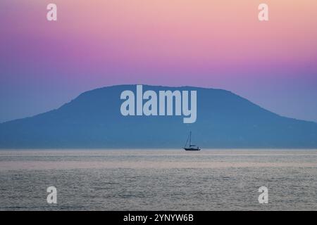 Segelboot vor dem Berg und der Stadt Badacsony bei Sonnenuntergang Stockfoto