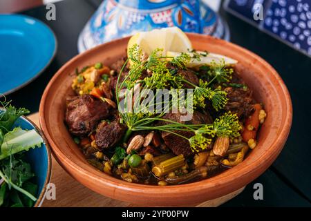 Traditionelle marokkanische Tagine mit Lammfleisch, Gemüse und Nüssen, serviert mit einem frischen Salat. Highlights lebhafte mediterrane Aromen und kulinarische Spezialitäten Stockfoto