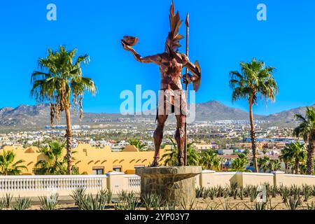 Eine Statue eines Kriegers steht vor einer Palme. Die Statue ist von einem üppig grünen Garten umgeben. Die Szene ist ruhig und friedlich, mit dem Stat Stockfoto