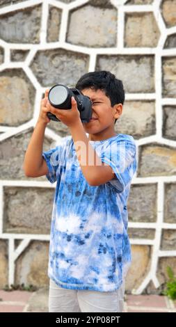 Der 10-jährige dunkelhäutige Latino Boy lernt eine professionelle Kamera zu benutzen, träumt und stellt sich vor, als Erwachsener zu arbeiten Stockfoto