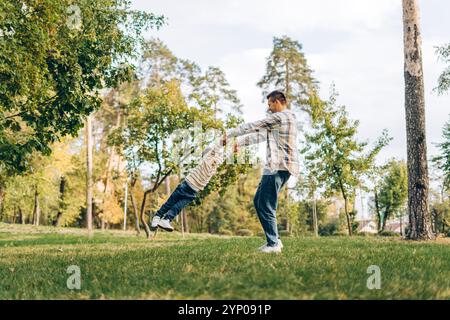 Porträt des glücklichen, lächelnden Vaters und des kleinen Sohnes, der zusammen im Park herumläuft, und Papas, der draußen spielt. Elternschaftskonzept Stockfoto