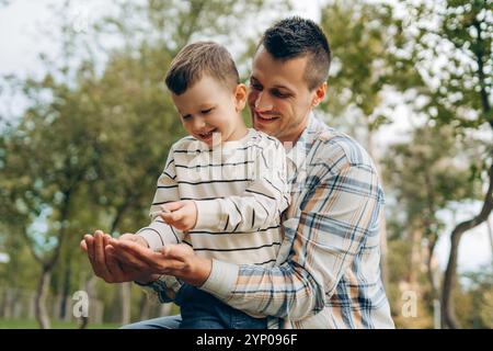 Lächelnde, glückliche Familie, positiver Vater und kleiner Sohn spielen zusammen im Park. Kindheit, Elternschaftskonzept Stockfoto