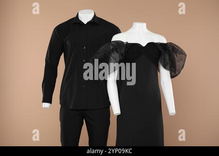 Weibliche und männliche Schaufensterpuppen mit stilvollen Outfits auf hellbraunem Hintergrund Stockfoto