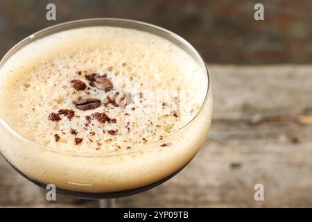 Köstlicher Espresso-Martini mit Kaffeebohnen im Glas vor verschwommenem Hintergrund, Nahaufnahme Stockfoto