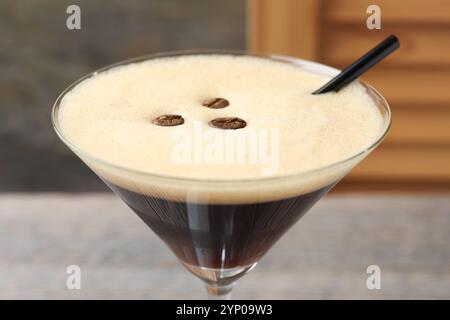 Köstlicher Espresso-Martini mit Kaffeebohnen im Glas vor verschwommenem Hintergrund, Nahaufnahme Stockfoto