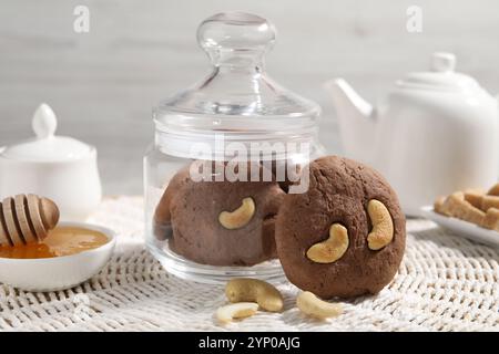 Leckere Schokoladenkekse mit Cashew und Honig auf Korbmatte, Nahaufnahme Stockfoto