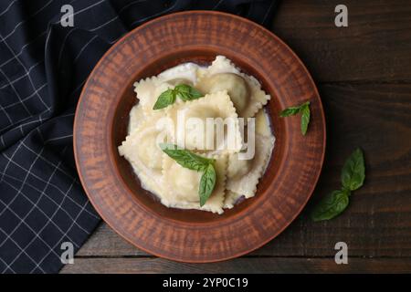 Köstliche Ravioli mit Käse und Basilikum serviert auf Holztisch, Blick von oben Stockfoto