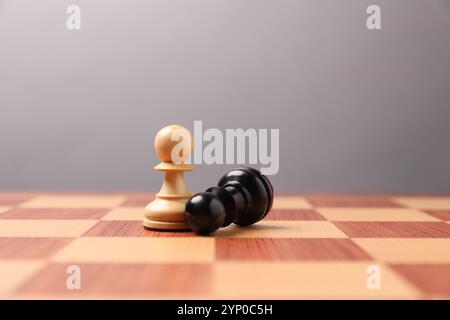 Weiße Schachfigur nahe gefallenem Schwarzen in der Mitte des Schachbretts. Wettbewerbskonzept Stockfoto