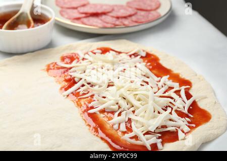 Zubereitung von Calzone-Pizza. Teig mit Sauce, Käse und anderen Zutaten auf dem Tisch, Nahaufnahme Stockfoto