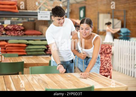 Ein junges verheiratetes Paar wählt einen Holztisch für seinen Garten im Gartenladen Stockfoto