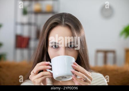 Gemütlicher Moment Eine junge Frau, die ihren Kaffee in einer schicken und stilvollen Umgebung in der Nähe genießt Stockfoto