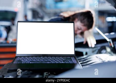 Mockup-Laptop mit verschwommenem Hintergrund des Reparaturmannes, der alte Autobremsflüssigkeit in der Werkstatt durch neue ersetzt. Isoliertes Bildschirmgerät und versierter Werkstattarbeiter, der Ausrüstung für die Kfz-Untersuchung verwendet Stockfoto
