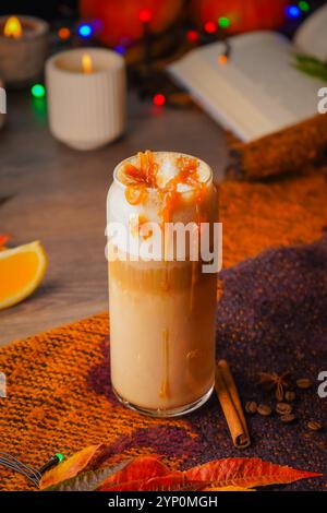 Kürbis gewürzte Latte in einem Glasbecher auf einem Vintage-Holzhintergrund. Heißgetränk im Herbst oder Winter. Selektiver Fokus Stockfoto