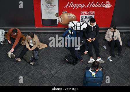 New York, USA. November 2024. Eine Gruppe von Reisenden sitzt am 27. November 2024 auf dem Boden im Terminal B des Flughafens LaGuardia am Thanksgiving-Vorabend in New York, NY. Es wird erwartet, dass mehr als 80 Millionen Reisende die Straßen, Züge und den Himmel nehmen, davon 6 Millionen fliegen. (Foto: Anthony Behar/SIPA USA) Credit: SIPA USA/Alamy Live News Stockfoto