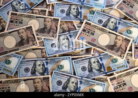 Muster von US-Dollar und japanischen Yen in großen 100- und 10.000-Yen-Banknoten, die ein Hintergrundbild der beiden Währungen erzeugen. Stockfoto