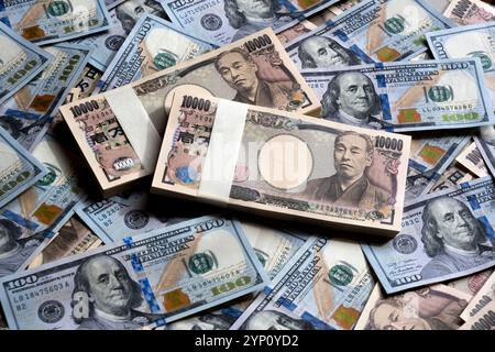 Muster von US-Dollar und japanischen Yen in großen 100- und 10.000-Yen-Banknoten, die ein Hintergrundbild der beiden Währungen erzeugen. Stockfoto