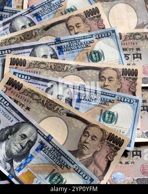 Muster von US-Dollar und japanischen Yen in großen 100- und 10.000-Yen-Banknoten, die ein Hintergrundbild der beiden Währungen erzeugen. Stockfoto
