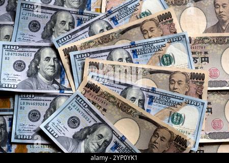Muster von US-Dollar und japanischen Yen in großen 100- und 10.000-Yen-Banknoten, die ein Hintergrundbild der beiden Währungen erzeugen. Stockfoto