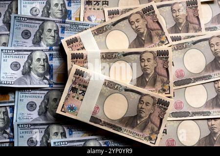 Muster von US-Dollar und japanischen Yen in großen 100- und 10.000-Yen-Banknoten, die ein Hintergrundbild der beiden Währungen erzeugen. Stockfoto